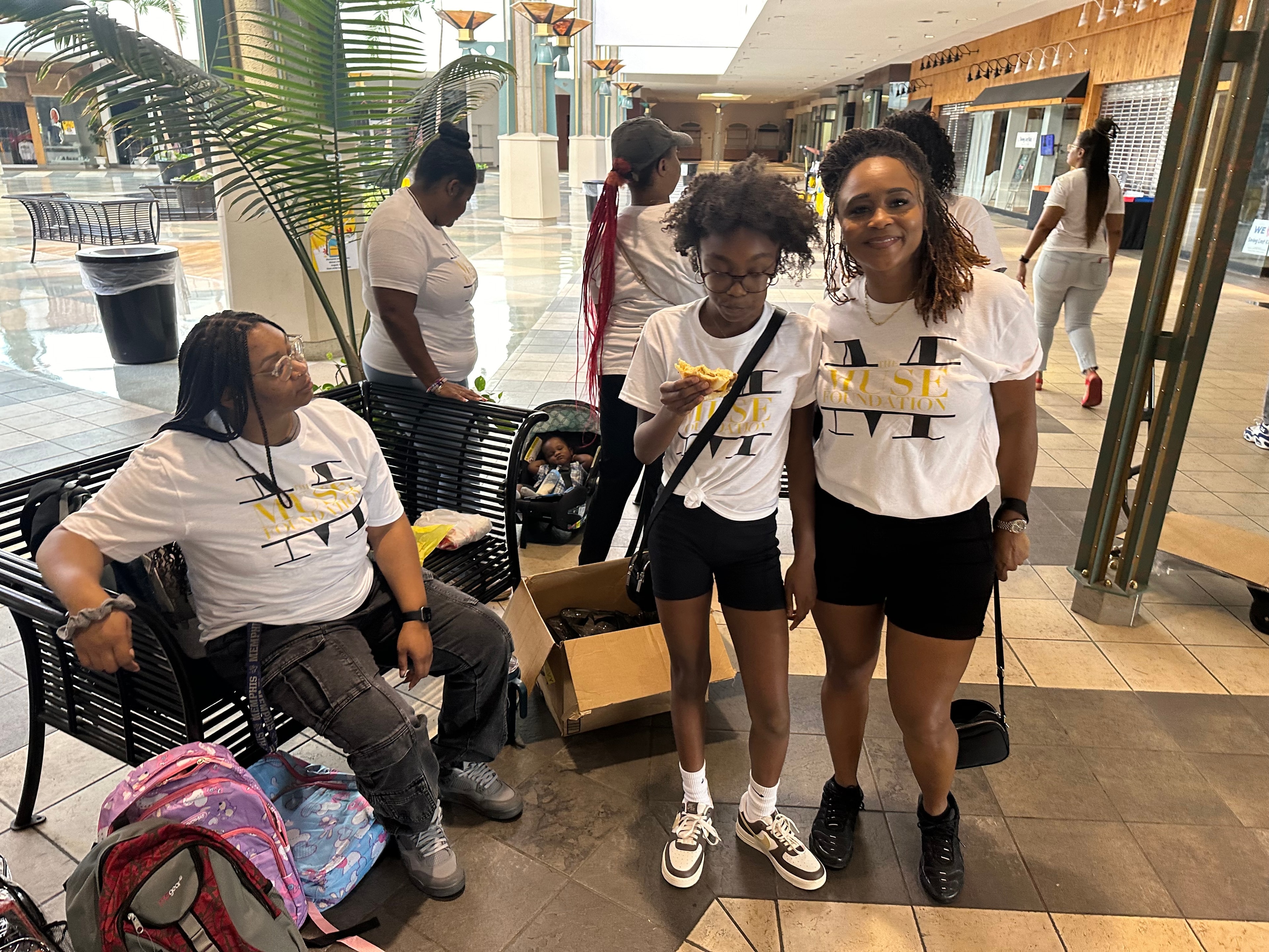 Muse Foundation volunteers in white t-shirts taking a break at the mall